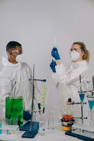 Two scientists in protective gear conducting chemical experiments in a lab.